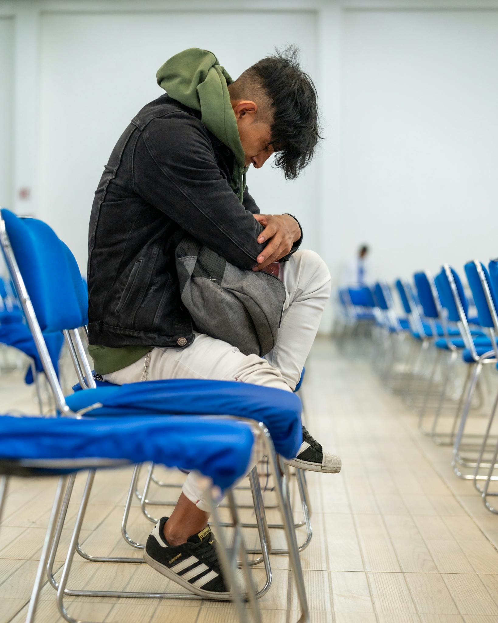 Photo par Israel Torres A man sitting on a blue chair with his head down